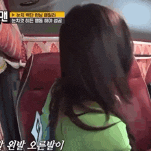 a woman in a green shirt is sitting in a red chair with korean writing on it