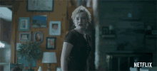 a woman is standing in a living room with a netflix logo on the bottom
