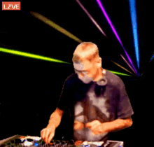 a man playing a dj set with a live sign above him