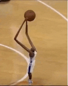 a basketball player with very long arms is holding a basketball in his hands .