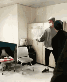 a man in a mask stands in a room with a chair