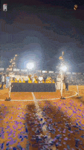 a group of people are standing in a stadium with purple confetti falling around them .