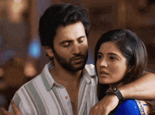a man with a beard is hugging a woman with a watch on her wrist