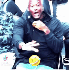 a man with red paint on his face is sitting in a chair with a smiley face behind him .