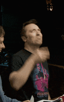 a man wearing a t-shirt that says ' apocalypse ' on it holds his fist in the air