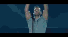 a man singing into a microphone with his arms up