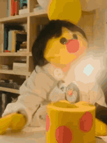 a yellow stuffed animal is sitting next to a yellow box with red dots on it