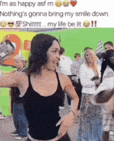 a woman in a black tank top is taking a selfie in front of a crowd .