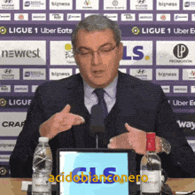 a man in a suit and tie is giving a speech in front of a screen that says acidobianconero