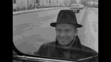 a man in a hat is smiling in a car