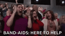 a group of people are screaming in a crowd while holding their hands up .