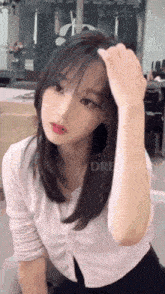 a woman is sitting in a chair with her hand on her head and looking at the camera .