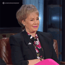 a woman wearing a black jacket and pink pants is smiling
