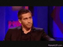 a man in a black suit is making a funny face