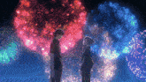 a man and a woman stand in front of a fireworks display
