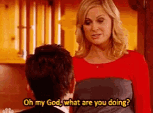 a woman is talking to a man in a kitchen and says oh my god what are you doing ?