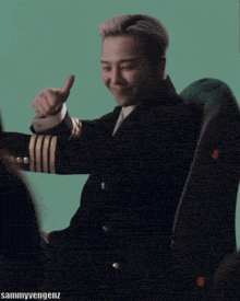 a man in a suit and tie is laughing while sitting in a chair with sammyvengenz written below him