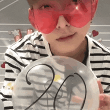 a person wearing red sunglasses is holding a clear balloon with the number 20 on it