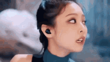 a close up of a woman wearing earbuds and looking up .