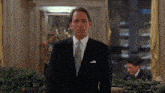 a man in a suit and tie is standing in front of a window with a sign that says ' abc ' on it