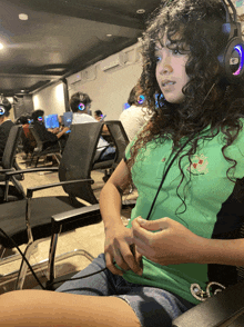 a girl with curly hair wearing a green shirt that says ' g ' on it