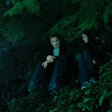 a man and a woman are sitting in a forest