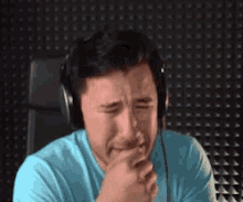 a man wearing headphones is crying with his hand to his mouth