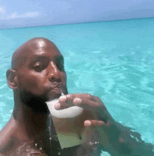 a man is drinking a drink from a plastic cup in the ocean