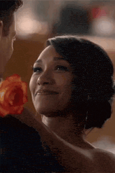 a man and a woman are dancing and the woman is smiling while holding a rose .