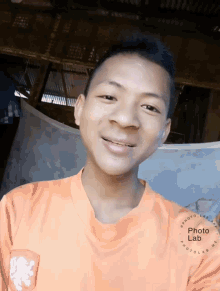 a young man wearing an orange shirt with a lion on the pocket smiles for the camera