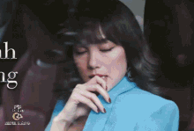 a woman wearing a blue jacket is covering her mouth with her hand .