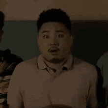 a man with a beard is making a surprised face while standing in a room .