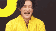 a man wearing a yellow jacket is smiling and clapping