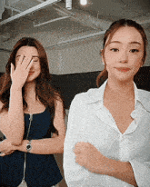 two women standing next to each other one covering her face
