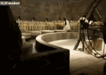 a man is standing in a dark room with a gif maker watermark on the bottom right