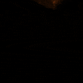 a woman 's face is lit up by a bright light in a dark room