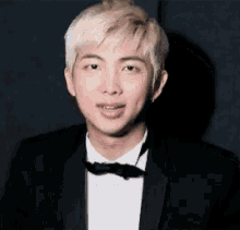 a close up of a young man wearing a suit and bow tie .