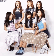 a group of girls are sitting in chairs and one of them has a skirt with the letter b on it