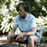 a woman wearing headphones is sitting on a wooden chair