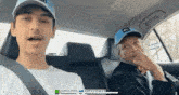 a man and a boy are sitting in the back seat of a car . the man is wearing a blue hat .