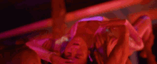 a woman is laying on her back in a dark room with a red light shining on her .