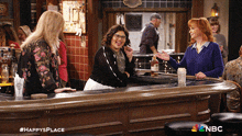 a group of women standing at a bar with a bottle of whiskey on the counter