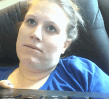 a woman in a blue shirt is sitting in a chair holding a keyboard