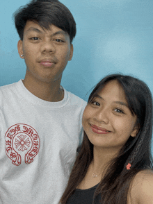 a man and a woman are posing for a picture with the man wearing a white shirt that says chrome hearts on it
