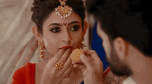 a man is feeding a woman a piece of food in front of her face