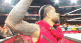 a man in a red jacket stands in a wrestling ring