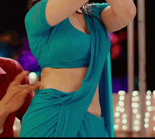 a woman in a blue crop top is being helped by a man in a red shirt