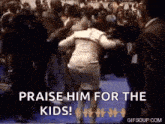 a woman is dancing in front of a crowd with the words `` praise him for the kids '' written on the bottom .
