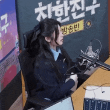 a woman is sitting in front of a microphone in front of a sign that says ' a ' on it