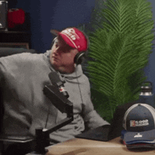 a man sitting in front of a microphone wearing headphones and a hat that says gop